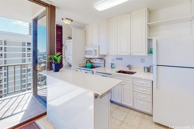 kitchen featuring stacked washer and dryer, white appliances, a sink, white cabinetry, and open shelves