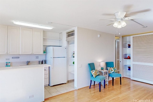 kitchen featuring open shelves, light countertops, light wood-style flooring, a ceiling fan, and freestanding refrigerator