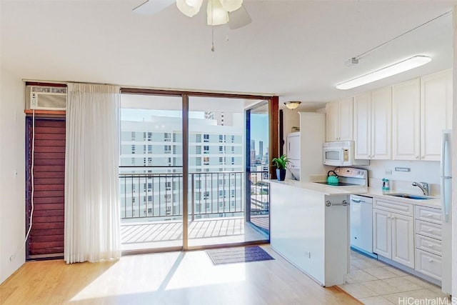 kitchen featuring floor to ceiling windows, stacked washer and dryer, white cabinets, a sink, and white appliances