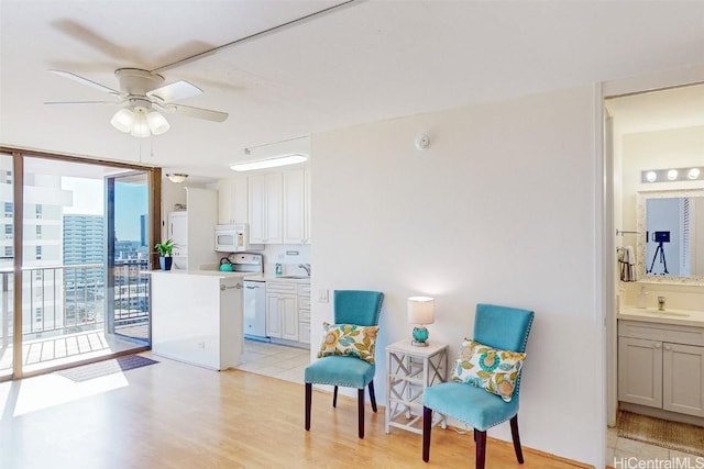 sitting room with light wood-style floors, floor to ceiling windows, and a ceiling fan