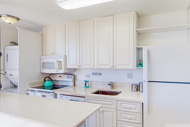 kitchen featuring stacked washer and dryer, white appliances, a sink, light countertops, and open shelves