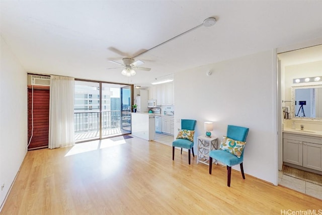 living area featuring floor to ceiling windows, ceiling fan, and light wood finished floors