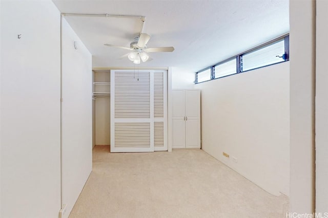 unfurnished bedroom with light carpet, ceiling fan, and a closet