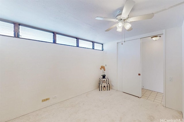 spare room featuring a textured ceiling, carpet, and a ceiling fan