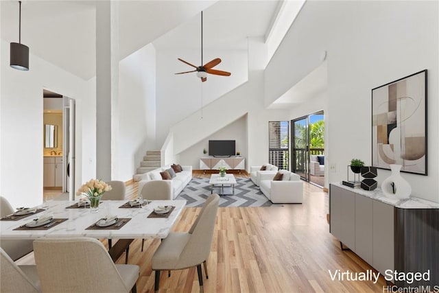 dining space with light hardwood / wood-style floors, ceiling fan, and a high ceiling