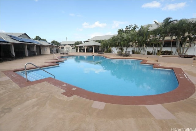 community pool with a patio area, fence, and a gazebo