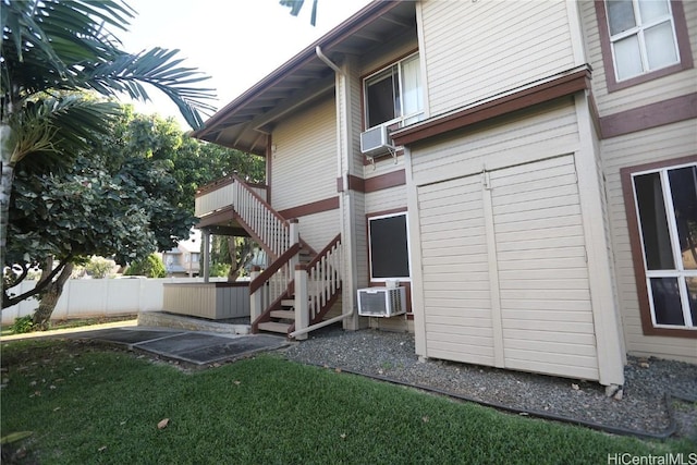 rear view of property featuring a patio, stairs, fence, an AC wall unit, and a yard