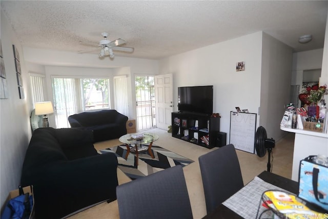 living room featuring light carpet, ceiling fan, and a textured ceiling