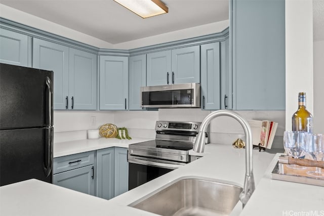 kitchen featuring a sink, blue cabinets, stainless steel appliances, and light countertops