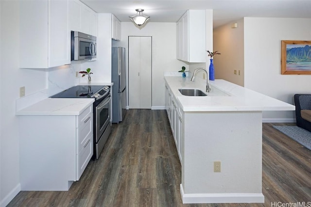 kitchen with kitchen peninsula, stainless steel appliances, dark hardwood / wood-style flooring, sink, and white cabinets