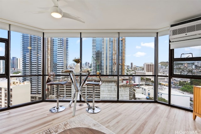 unfurnished sunroom featuring ceiling fan and a wall unit AC