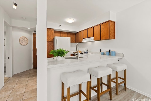 kitchen with a kitchen breakfast bar, white fridge, sink, and kitchen peninsula