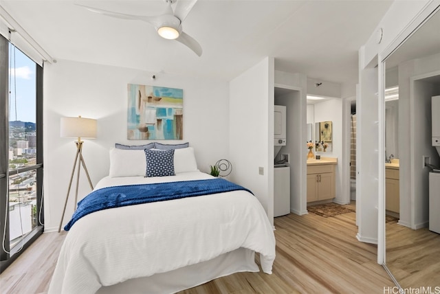 bedroom featuring ceiling fan, expansive windows, light hardwood / wood-style floors, and ensuite bath