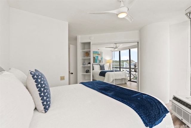 bedroom with hardwood / wood-style floors, ceiling fan, an AC wall unit, and access to exterior