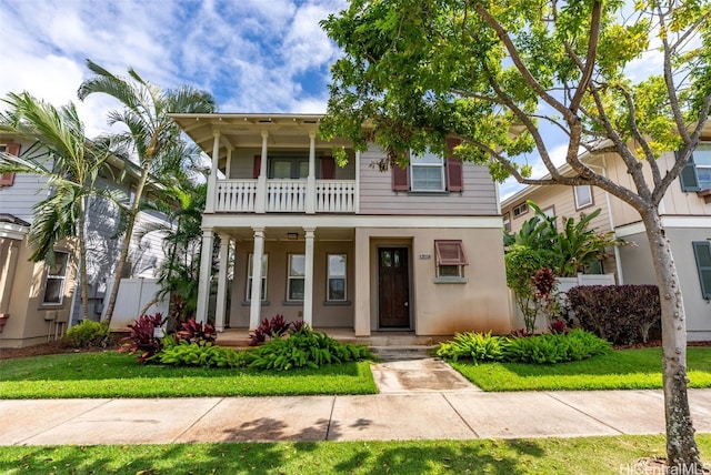 view of front facade with covered porch, a front yard, and a balcony