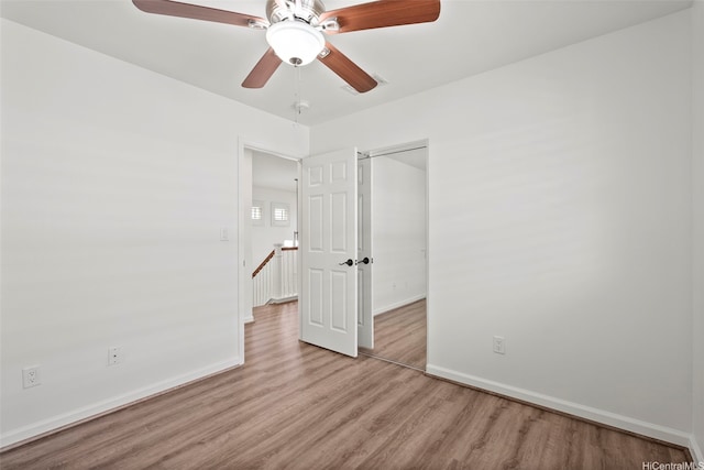 unfurnished bedroom featuring baseboards, wood finished floors, a ceiling fan, and a closet