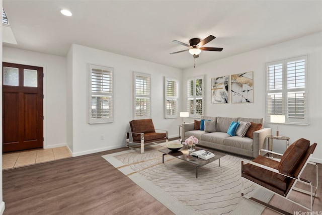 living room featuring light wood-style flooring, ceiling fan, a wealth of natural light, and baseboards