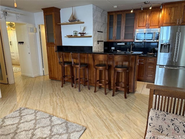 kitchen with stainless steel appliances, backsplash, a breakfast bar area, and sink