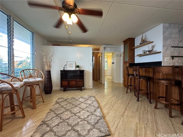 sitting room featuring bar and ceiling fan