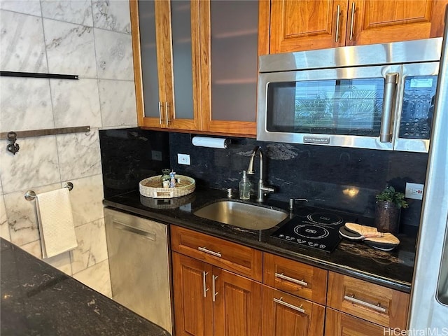 kitchen with sink, appliances with stainless steel finishes, dark stone countertops, and tasteful backsplash