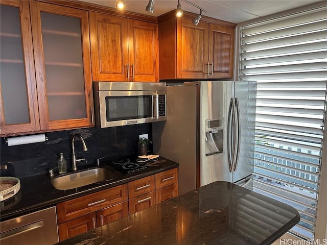 kitchen with appliances with stainless steel finishes, sink, dark stone counters, and tasteful backsplash