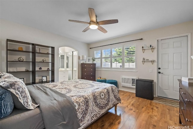 bedroom featuring light wood-style flooring, arched walkways, ceiling fan, and ensuite bathroom