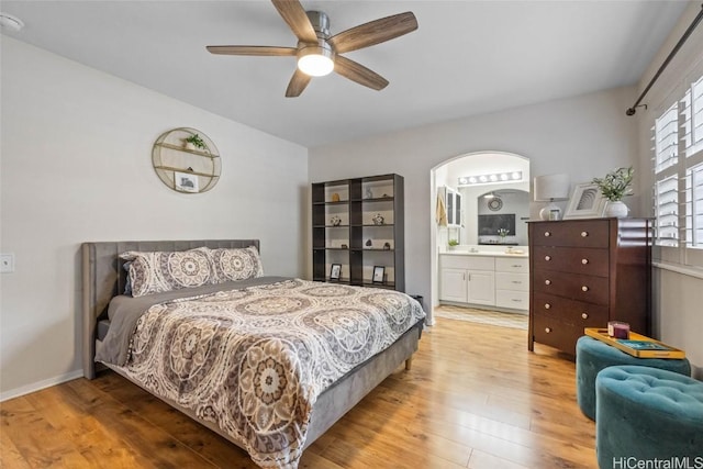 bedroom with baseboards, ceiling fan, ensuite bath, and wood finished floors