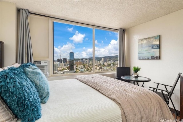 bedroom with a view of city, a textured ceiling, and a wall mounted air conditioner