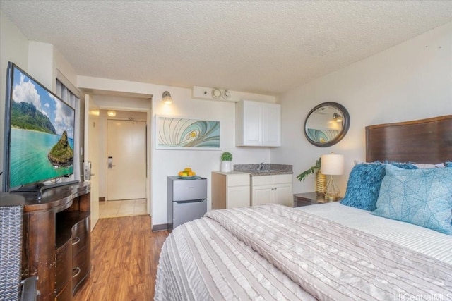 bedroom with a sink, light wood-style flooring, and a textured ceiling