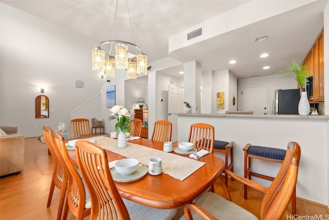 dining area featuring light hardwood / wood-style floors and a notable chandelier