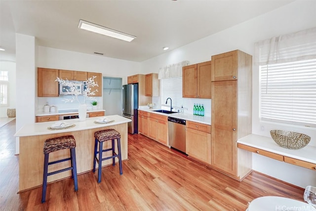 kitchen with appliances with stainless steel finishes, light countertops, light wood finished floors, and a kitchen bar