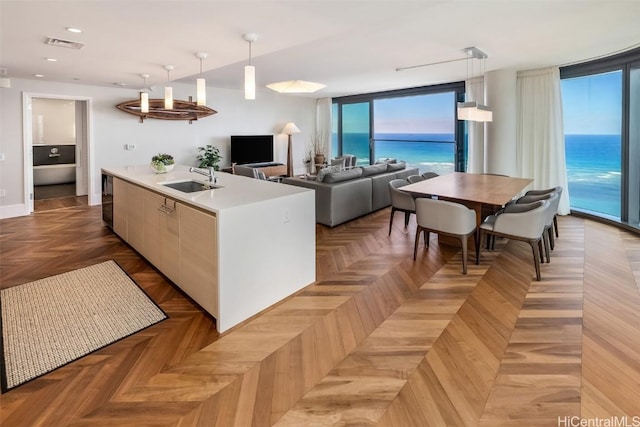 kitchen featuring visible vents, an island with sink, modern cabinets, pendant lighting, and a sink