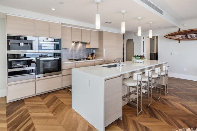 kitchen with arched walkways, a sink, visible vents, appliances with stainless steel finishes, and tasteful backsplash