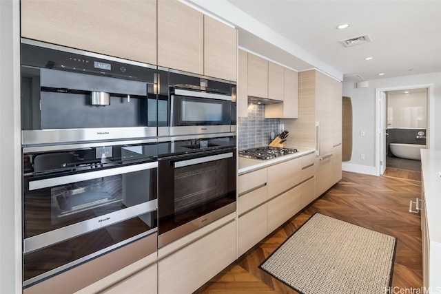 kitchen featuring tasteful backsplash, light countertops, visible vents, stainless steel gas stovetop, and modern cabinets