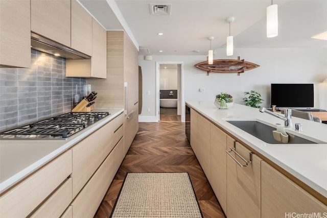 kitchen featuring stainless steel gas cooktop, a sink, visible vents, light countertops, and tasteful backsplash