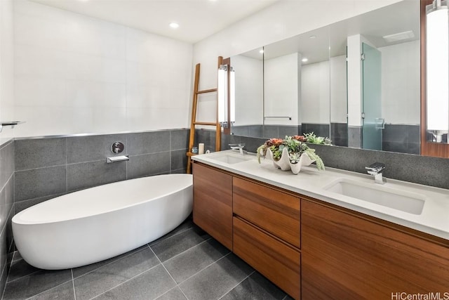 full bathroom featuring double vanity, a soaking tub, a sink, and tile patterned floors