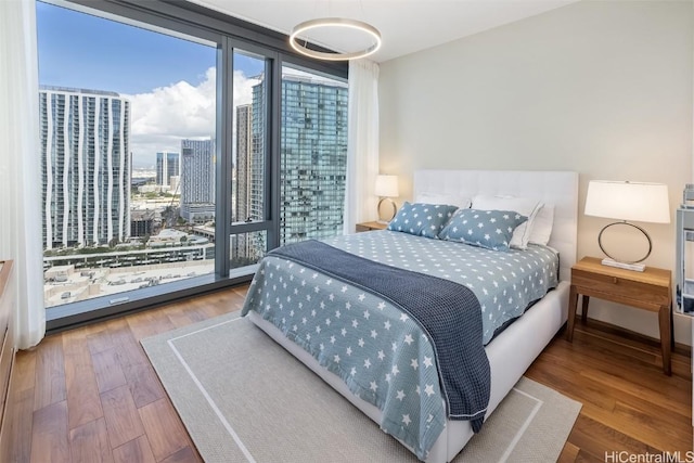 bedroom with access to outside, a city view, and wood finished floors