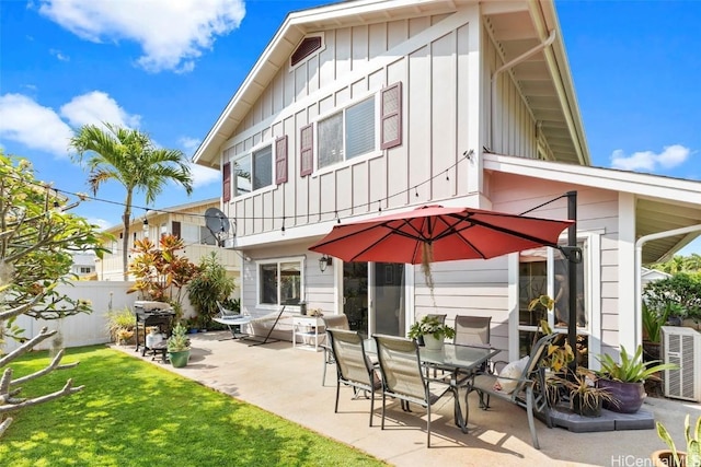 rear view of property featuring a patio, board and batten siding, fence, and a lawn