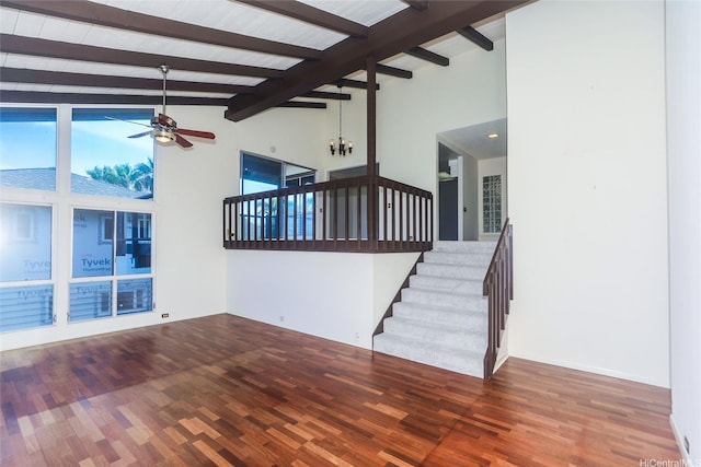 unfurnished living room with stairs, ceiling fan, beam ceiling, and wood finished floors