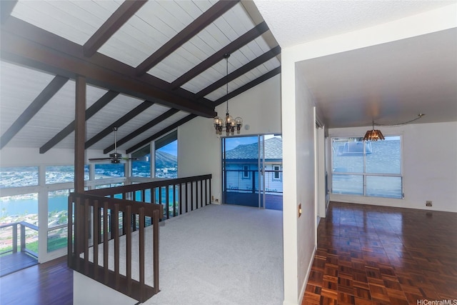 hall with lofted ceiling with beams, a wealth of natural light, and a chandelier