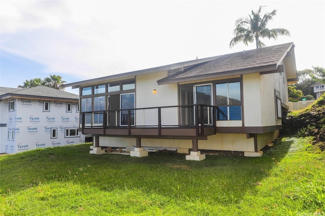 back of house featuring stucco siding and a lawn