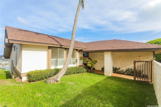 ranch-style house featuring a front yard, a shingled roof, and stucco siding