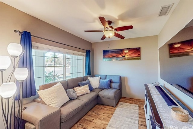 living room featuring a ceiling fan, visible vents, and wood finished floors