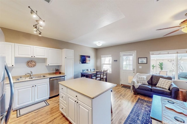 kitchen featuring light countertops, light wood-style flooring, open floor plan, a sink, and dishwasher