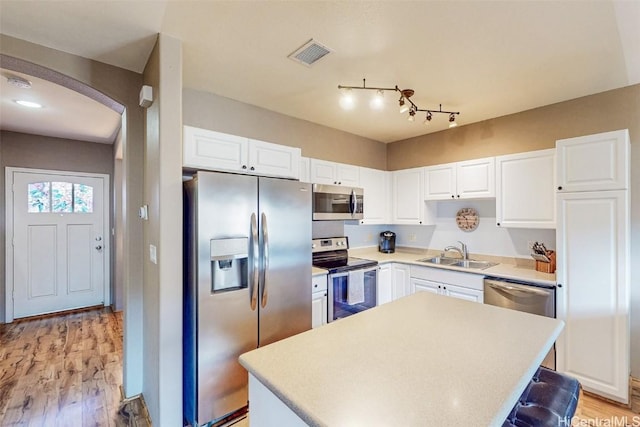 kitchen with arched walkways, stainless steel appliances, visible vents, white cabinets, and a sink