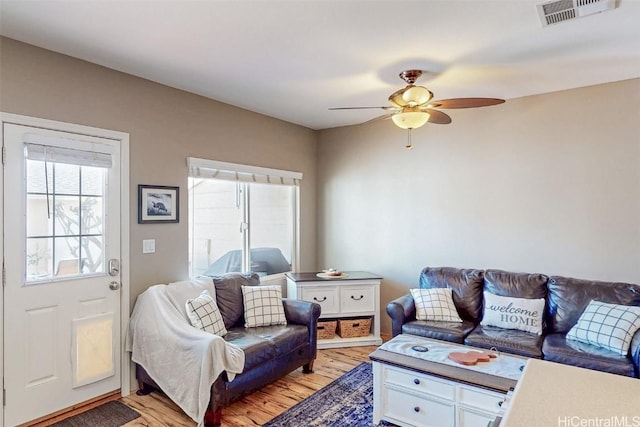 living area featuring a ceiling fan, visible vents, and light wood finished floors