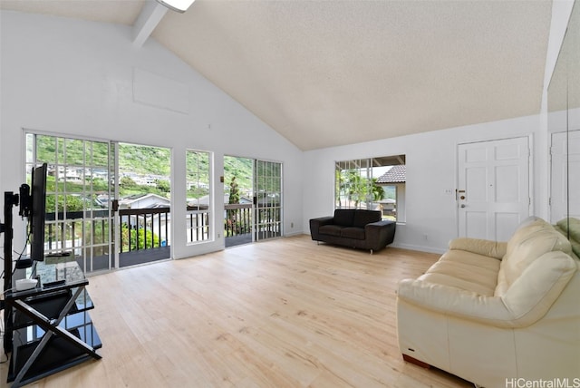 living area featuring beam ceiling, a textured ceiling, wood finished floors, high vaulted ceiling, and baseboards