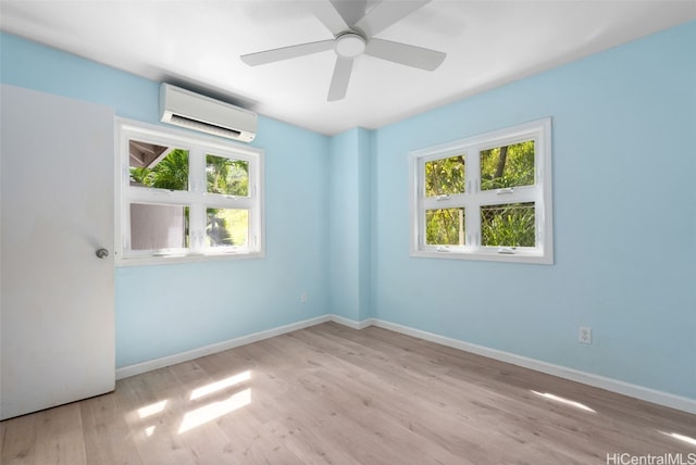 spare room featuring plenty of natural light, a wall unit AC, wood finished floors, and baseboards