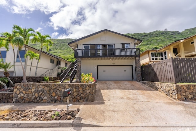 view of front of property with driveway, an attached garage, stairs, and fence