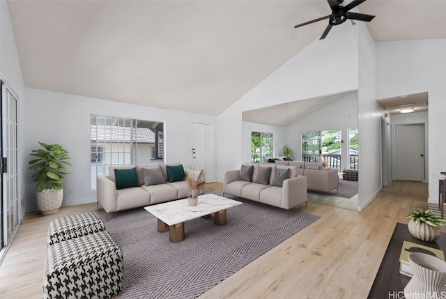 living area with ceiling fan, high vaulted ceiling, light wood finished floors, and baseboards